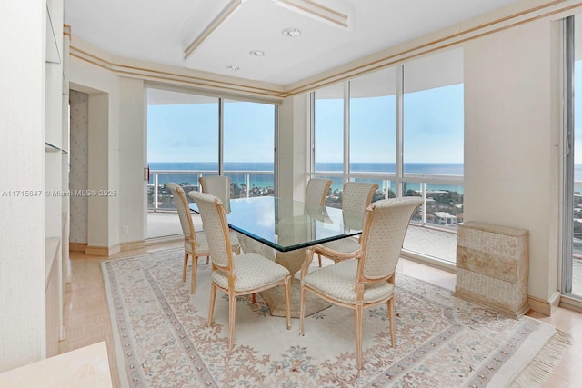 dining space with a water view, a wall of windows, and light parquet floors