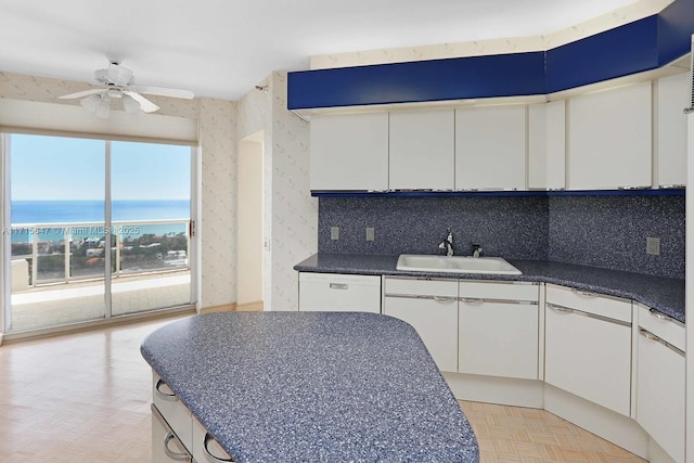 kitchen featuring a water view, white cabinetry, sink, and light parquet floors