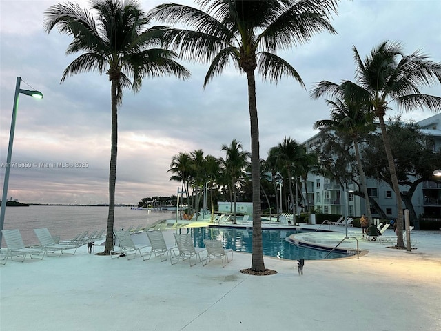 view of pool featuring a water view and a patio area