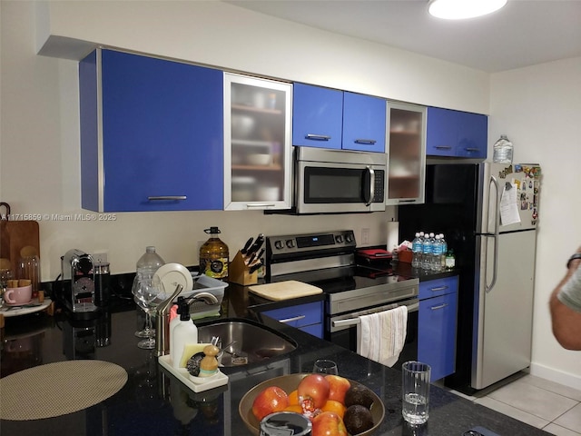 kitchen with blue cabinets, light tile patterned floors, sink, and appliances with stainless steel finishes