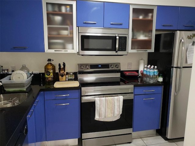 kitchen with sink, light tile patterned floors, stainless steel appliances, and blue cabinetry