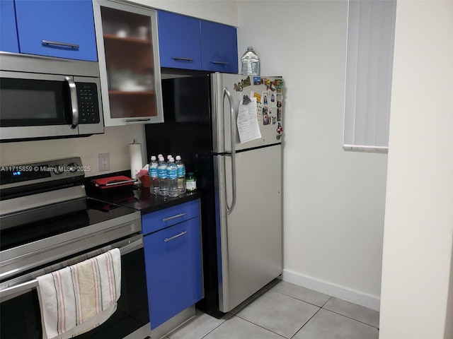 kitchen with blue cabinets, light tile patterned floors, and appliances with stainless steel finishes