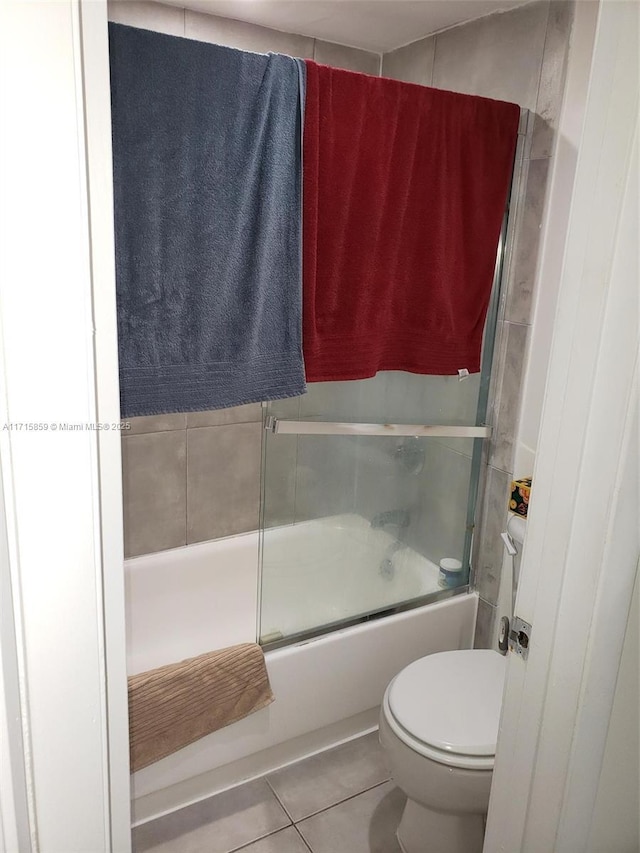 bathroom with tile patterned floors, enclosed tub / shower combo, and toilet