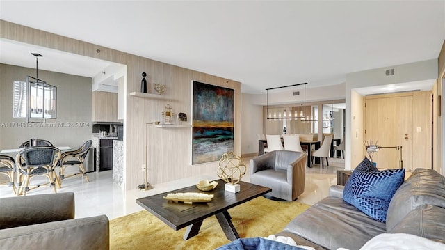 living room featuring a chandelier and wood walls