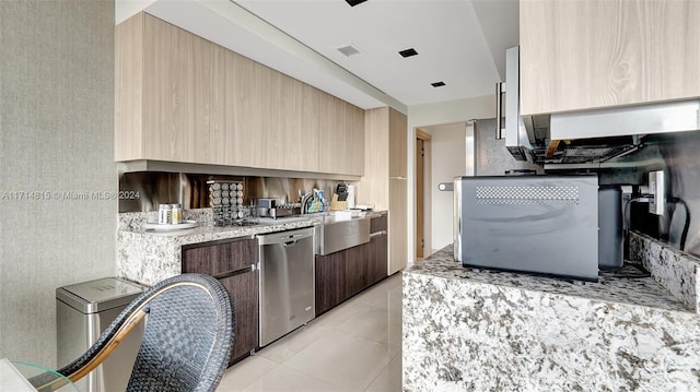 kitchen with light stone countertops, light tile patterned flooring, and stainless steel dishwasher