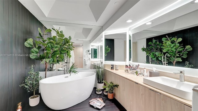 bathroom featuring vanity, a tub, and wood walls