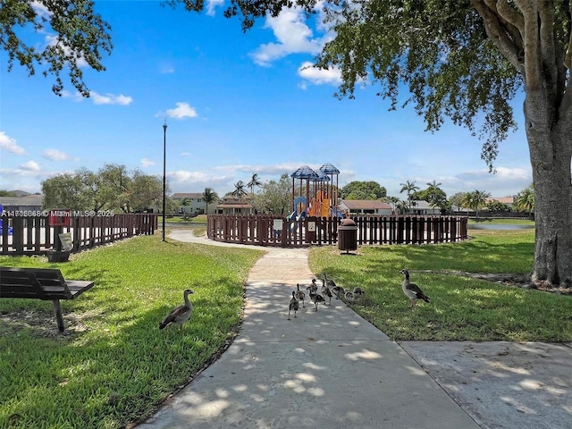 view of property's community with a playground and a lawn