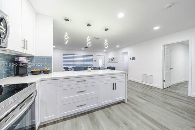 kitchen featuring decorative light fixtures, stainless steel electric range, and white cabinets