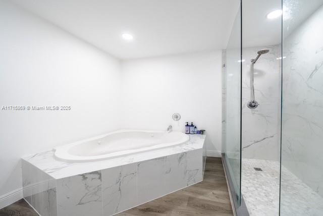 bathroom featuring plus walk in shower and hardwood / wood-style floors