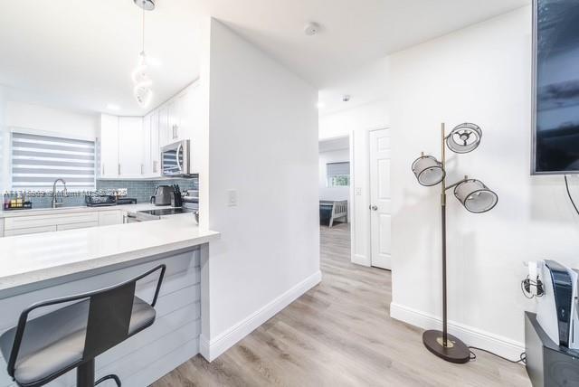 kitchen with pendant lighting, sink, white cabinetry, stove, and decorative backsplash