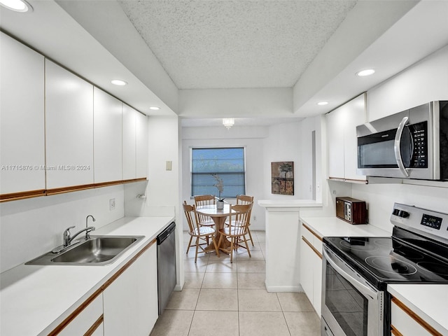 kitchen featuring white cabinetry, sink, a textured ceiling, light tile patterned floors, and appliances with stainless steel finishes