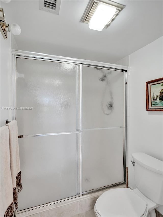 bathroom with a shower with door and toilet