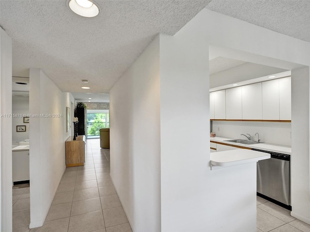 corridor with sink, light tile patterned floors, and a textured ceiling