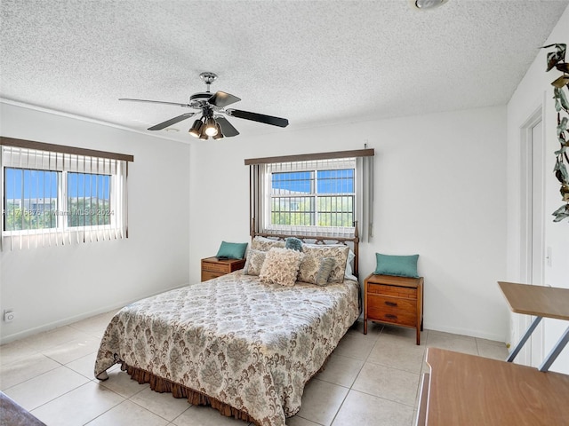 bedroom with ceiling fan, light tile patterned floors, and a textured ceiling