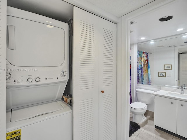 laundry area featuring stacked washer / drying machine, light tile patterned floors, and sink