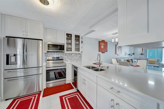 kitchen with decorative backsplash, sink, white cabinetry, and stainless steel appliances