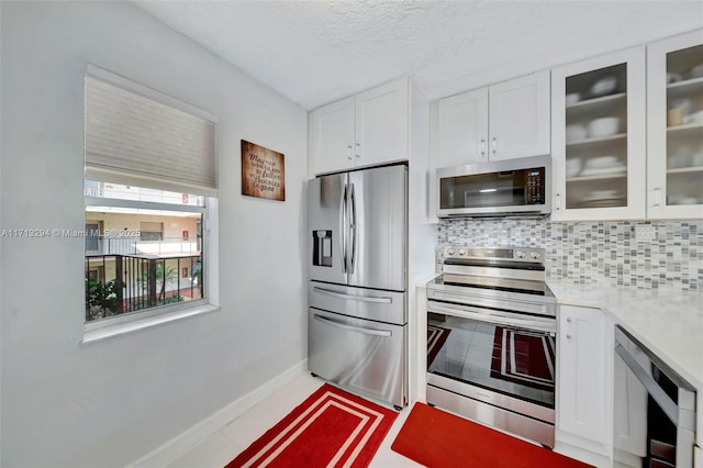 kitchen featuring stainless steel appliances, white cabinetry, a textured ceiling, and tasteful backsplash