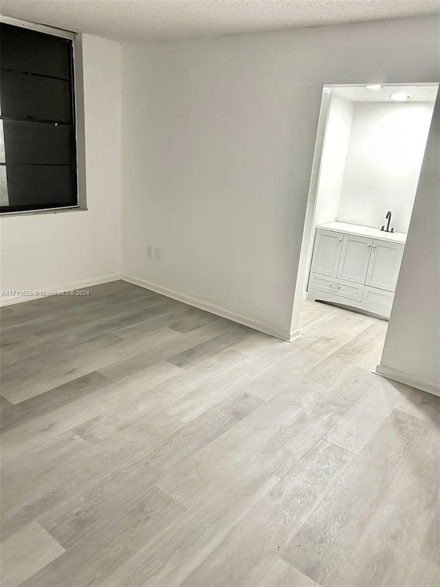 unfurnished room with light hardwood / wood-style flooring and a textured ceiling