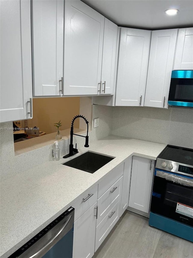 kitchen featuring light hardwood / wood-style flooring, sink, stainless steel appliances, and white cabinetry