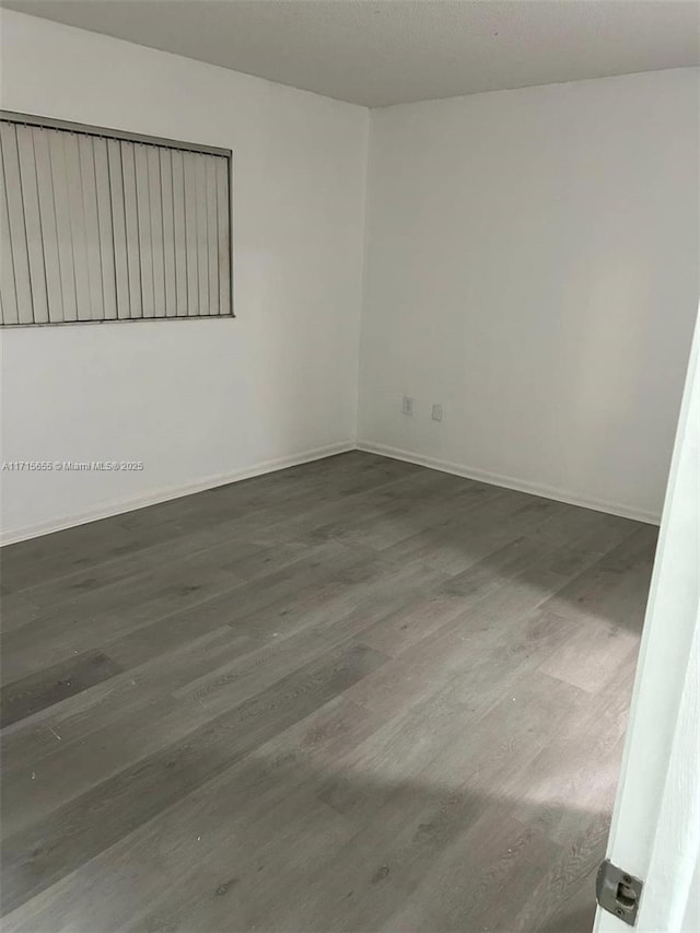 unfurnished room with dark hardwood / wood-style flooring