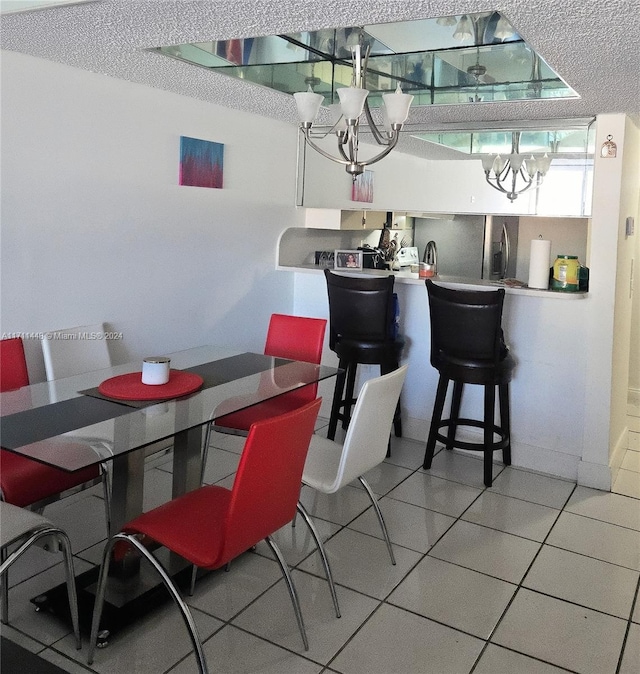 tiled dining space featuring a chandelier and a textured ceiling