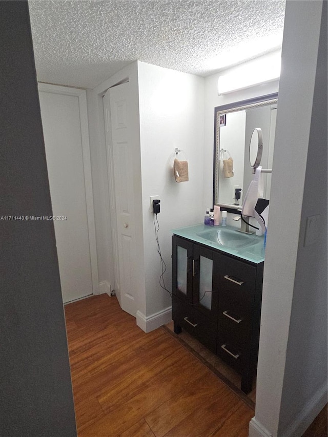 bathroom with wood-type flooring, vanity, and a textured ceiling