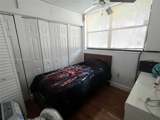 bedroom with two closets, ceiling fan, dark wood-type flooring, and a textured ceiling