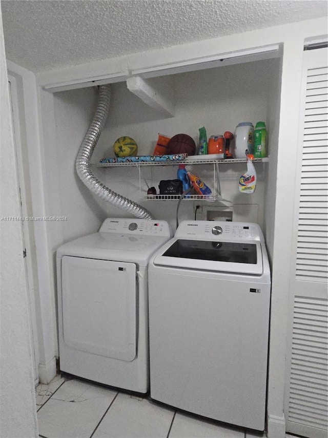 clothes washing area featuring a textured ceiling and washing machine and clothes dryer