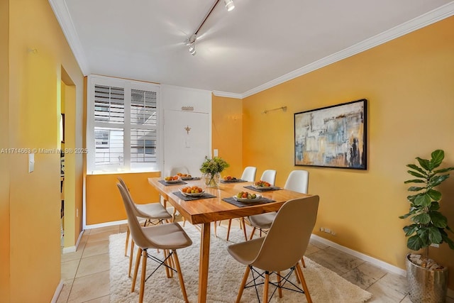 tiled dining area featuring rail lighting and ornamental molding