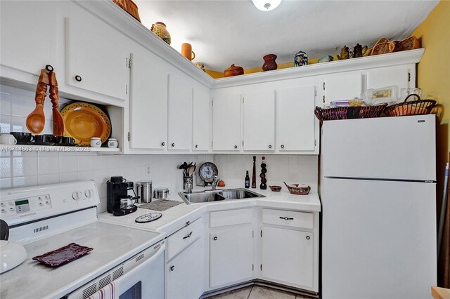 kitchen with stove, white refrigerator, white cabinetry, and backsplash