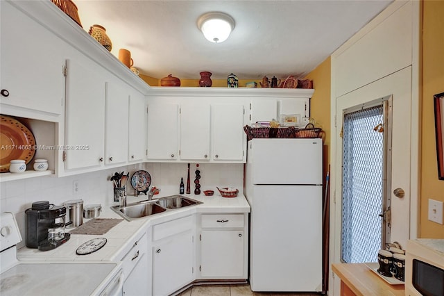 kitchen featuring backsplash, white refrigerator, sink, white cabinetry, and range