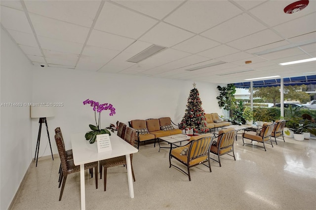 living room featuring a paneled ceiling and a wall of windows