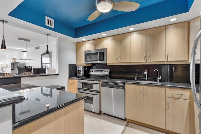 kitchen featuring light brown cabinetry, pendant lighting, light tile patterned flooring, and stainless steel appliances