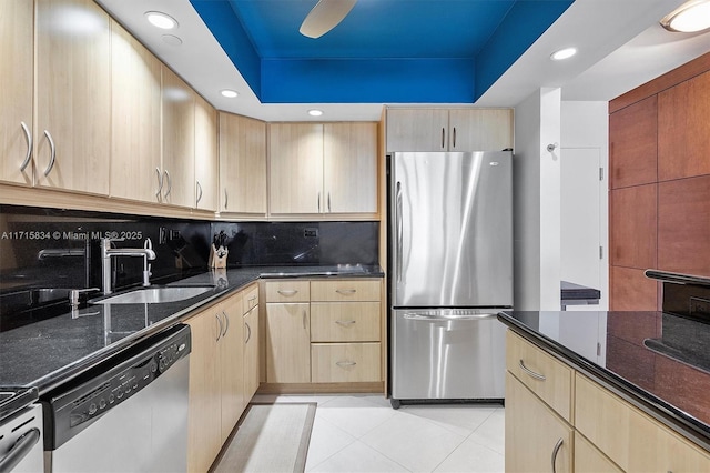 kitchen with dark stone countertops, light tile patterned floors, stainless steel appliances, and light brown cabinetry