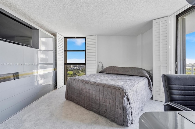 bedroom with a textured ceiling, light colored carpet, and multiple windows