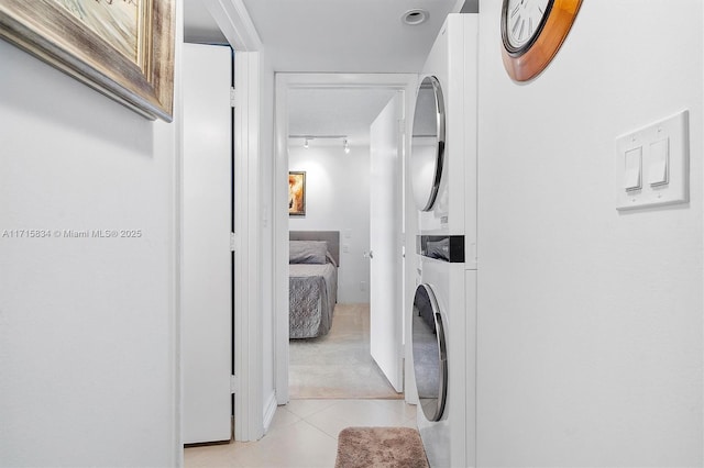 laundry area with light tile patterned floors and stacked washer and dryer