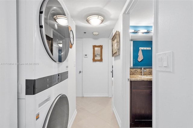 clothes washing area featuring stacked washer / drying machine, light tile patterned flooring, and sink