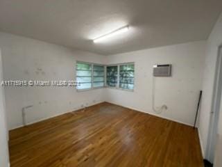 spare room featuring dark hardwood / wood-style flooring and a wall unit AC