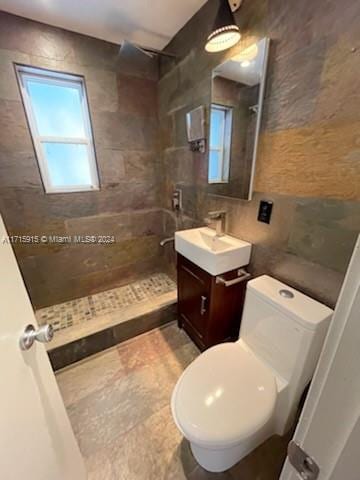 bathroom featuring vanity, toilet, and a tile shower