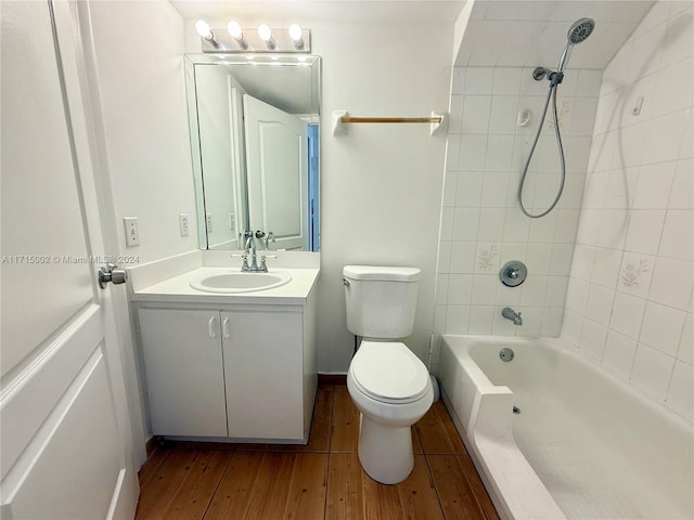 full bathroom with tiled shower / bath, vanity, wood-type flooring, and toilet