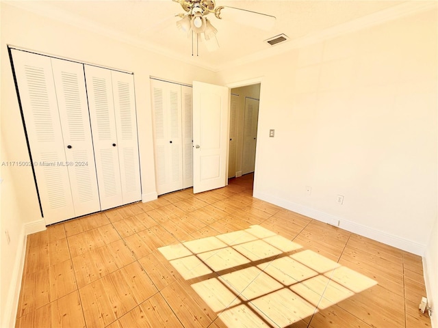 unfurnished bedroom with multiple closets, ceiling fan, and crown molding