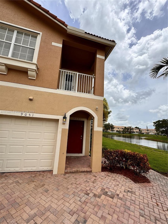 exterior space featuring a balcony, a water view, and a garage