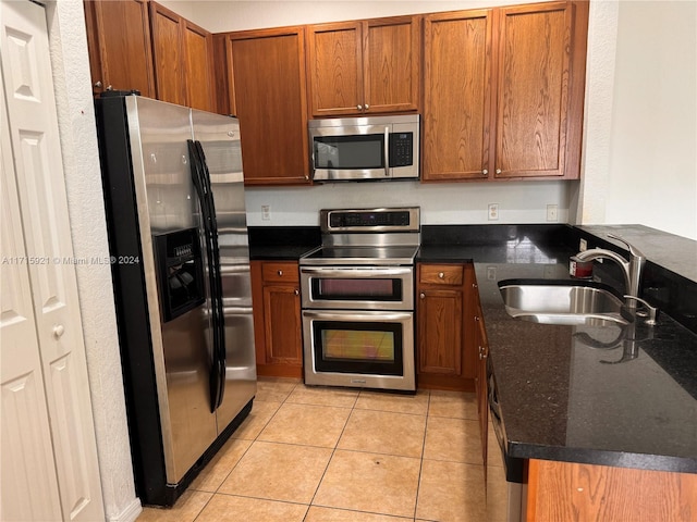 kitchen featuring light tile patterned flooring, stainless steel appliances, kitchen peninsula, and sink