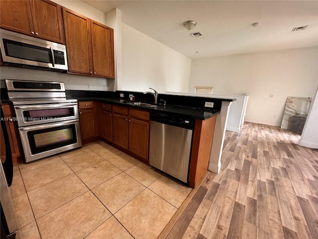 kitchen featuring sink, light hardwood / wood-style flooring, appliances with stainless steel finishes, kitchen peninsula, and a breakfast bar area