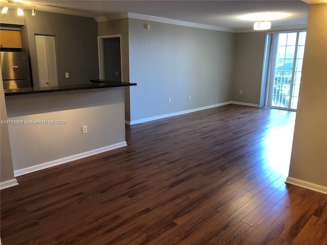 unfurnished living room with a textured ceiling, ornamental molding, and dark wood-type flooring