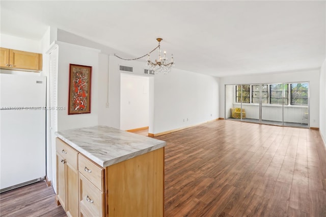 kitchen featuring kitchen peninsula, light brown cabinetry, dark hardwood / wood-style flooring, an inviting chandelier, and white fridge