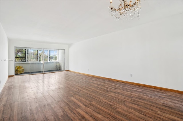 empty room with an inviting chandelier and dark wood-type flooring