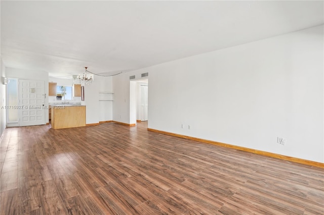 unfurnished living room featuring a chandelier and dark wood-type flooring