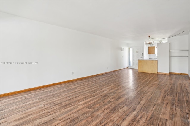 unfurnished living room with hardwood / wood-style flooring and a notable chandelier