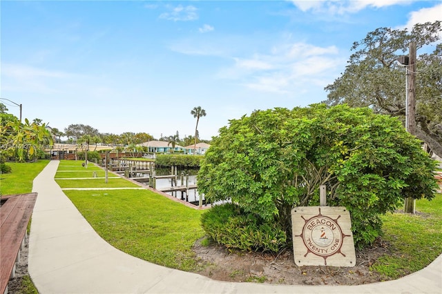 view of community with a yard, a water view, and a boat dock